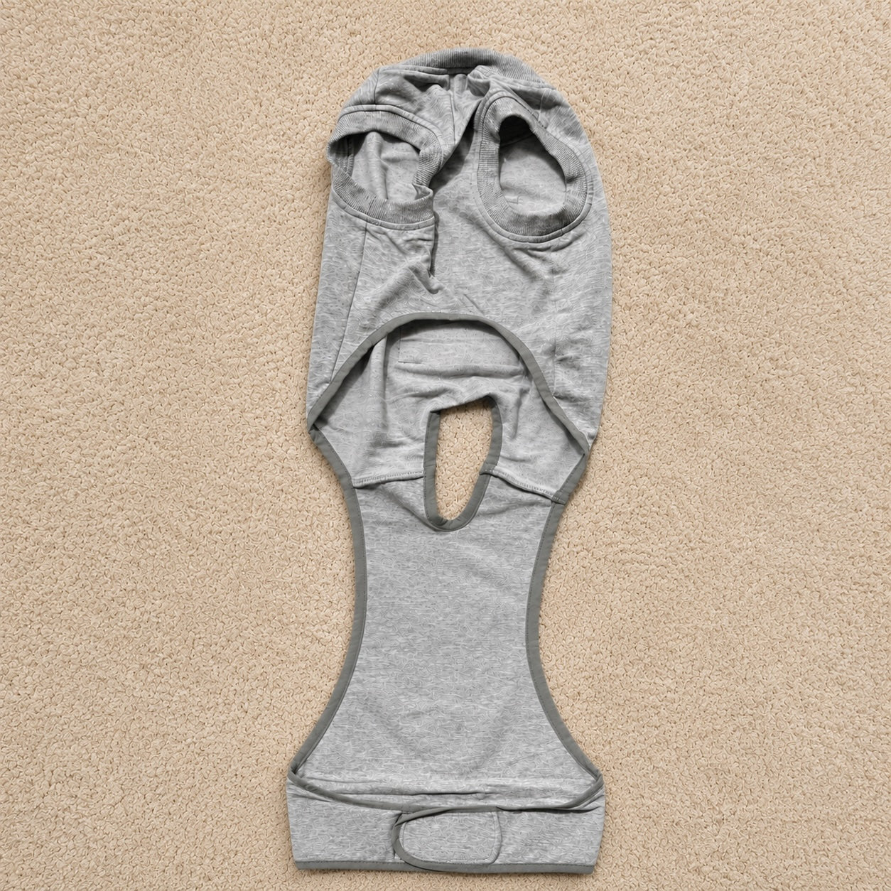 Gray dog recovery suit laid flat, showing the full-body onesie design and adjustable fit for after-surgery care